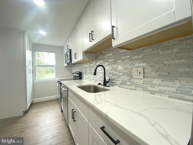 1319 Rainer Rd, Brookhaven, PA 19015 - kitchen with stainless steel appliances, light wood finished floors, backsplash, and white cabinets