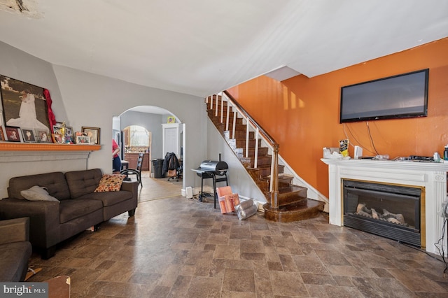 5503 Beaumont Ave, Philadelphia, PA 19143 - living room featuring stone finish flooring, arched walkways, stairway, and a glass covered fireplace