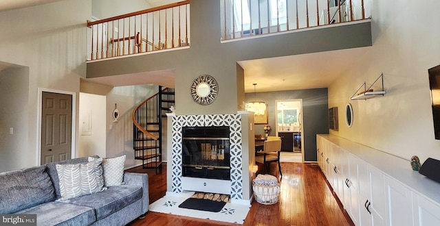 11492 Corinthia Ct, Woodbridge, VA 22192 - living room featuring stairs, wood finished floors, a towering ceiling, and a tile fireplace