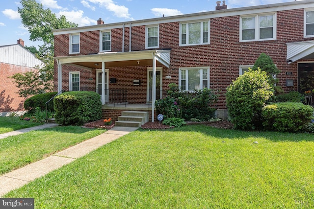833 Evesham Ave, Baltimore, MD 21212 - view of front facade featuring a chimney, brick siding, and a front yard