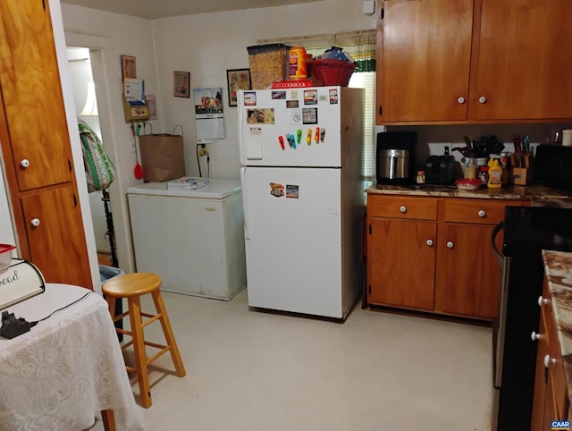 1411 Vine St, Charlottesville, VA 22902 - kitchen with freestanding refrigerator, refrigerator, range, brown cabinets, and black microwave