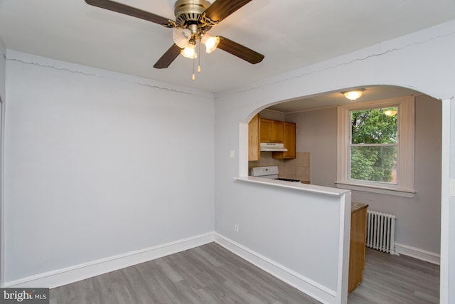 7152 N 20th St, Philadelphia, PA 19138 - kitchen featuring radiator heating unit, under cabinet range hood, range, and arched walkways