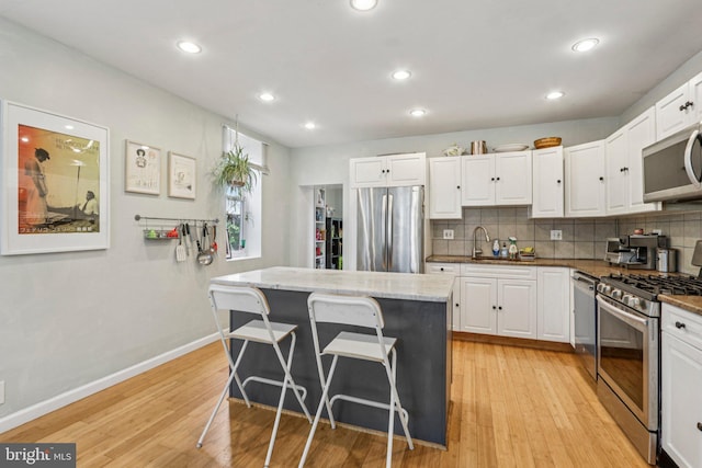 455 Krams Ave, Philadelphia, PA 19128 - kitchen featuring stainless steel appliances, white cabinets, backsplash, a breakfast bar, and recessed lighting