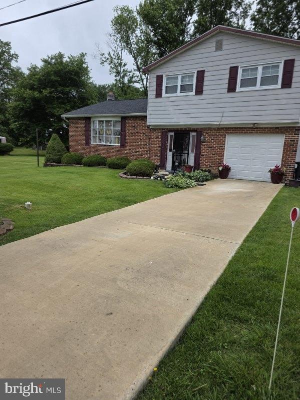 30 Belvue Ter, Aston, PA 19014 - split level home featuring brick siding, a garage, a front lawn, driveway, and a chimney