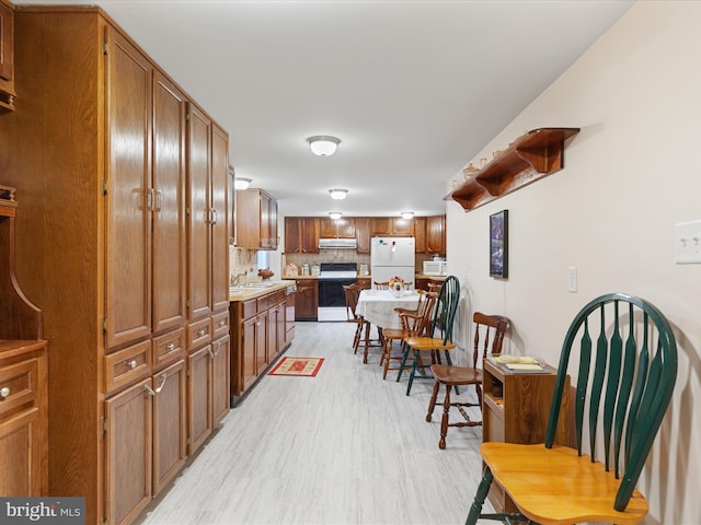 5409 Greenspring Valley Rd, Green Spring, WV 26722 - kitchen with white appliances, under cabinet range hood, light wood finished floors, and brown cabinets