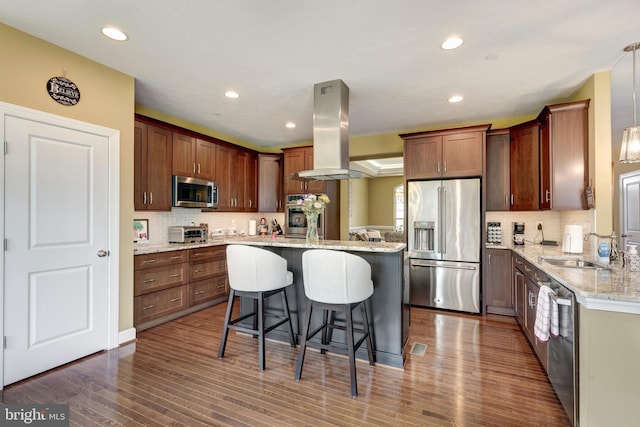4136 Shanelle Ct Lot 10, Hampstead, MD 21074 - kitchen featuring appliances with stainless steel finishes, island exhaust hood, a breakfast bar area, decorative backsplash, and a center island