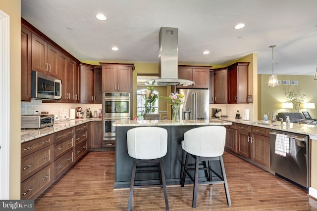 4136 Shanelle Ct Lot 10, Hampstead, MD 21074 - kitchen featuring stainless steel appliances, island range hood, a center island, a breakfast bar area, and wood finished floors