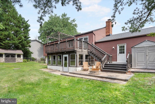 1215 Lorene Dr, Pasadena, MD 21122 - rear view of house featuring a shed, a deck, a lawn, a chimney, and an outdoor fire pit