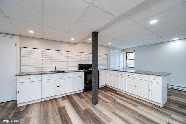 27 E Spring St, Frackville, PA 17931 - kitchen featuring a peninsula, black electric range, white cabinets, light wood-style flooring, and a drop ceiling