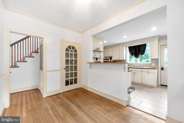 824 Lindale Ave, Drexel Hill, PA 19026 - kitchen with light wood-style floors, ornamental molding, decorative backsplash, a peninsula, and white cabinets