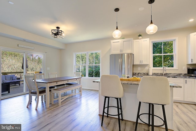 8207 Elm Ln, Chesapeake Beach, MD 20732 - kitchen featuring stainless steel appliances, light wood finished floors, a breakfast bar, white cabinetry, and a center island