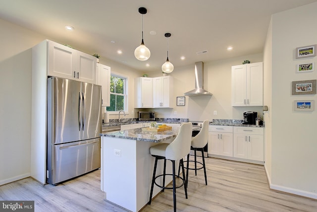 8207 Elm Ln, Chesapeake Beach, MD 20732 - kitchen with appliances with stainless steel finishes, wall chimney range hood, a breakfast bar area, white cabinets, and a kitchen island