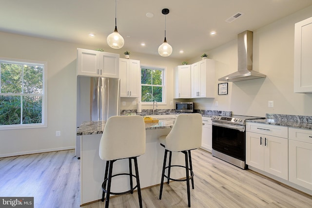 8207 Elm Ln, Chesapeake Beach, MD 20732 - kitchen with wall chimney range hood, appliances with stainless steel finishes, light wood-style floors, stone countertops, and white cabinetry