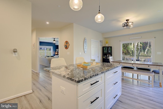 8207 Elm Ln, Chesapeake Beach, MD 20732 - kitchen featuring light wood-type flooring, dark stone countertops, a kitchen island, and plenty of natural light