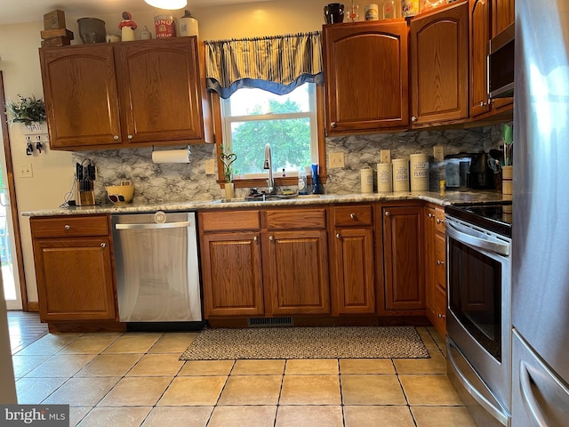 10474 Mapleton Rd, Shippensburg, PA 17257 - kitchen with appliances with stainless steel finishes, tasteful backsplash, light tile patterned flooring, and brown cabinetry
