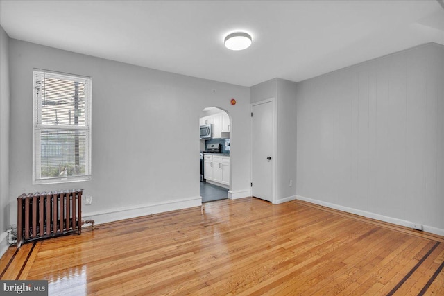 1528 Park Blvd, Camden, NJ 08103 - spare room featuring radiator, arched walkways, and light wood-type flooring