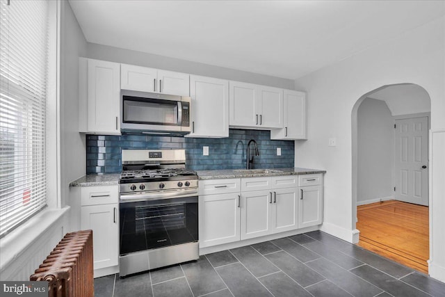 1528 Park Blvd, Camden, NJ 08103 - kitchen featuring appliances with stainless steel finishes, radiator heating unit, backsplash, and white cabinetry