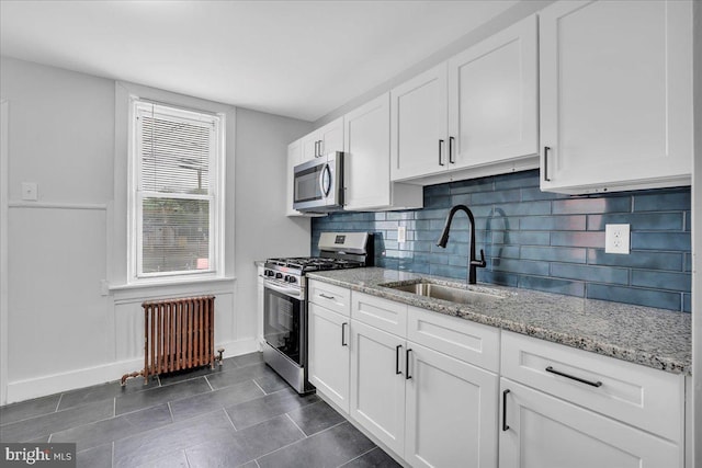 1528 Park Blvd, Camden, NJ 08103 - kitchen with stainless steel appliances, radiator, white cabinets, decorative backsplash, and dark tile patterned flooring