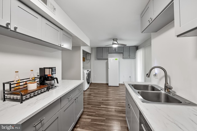 7702 Hanover Pkwy Unit 301, Greenbelt, MD 20770 - kitchen with washer and clothes dryer, gray cabinetry, dark wood-type flooring, ceiling fan, and light stone counters