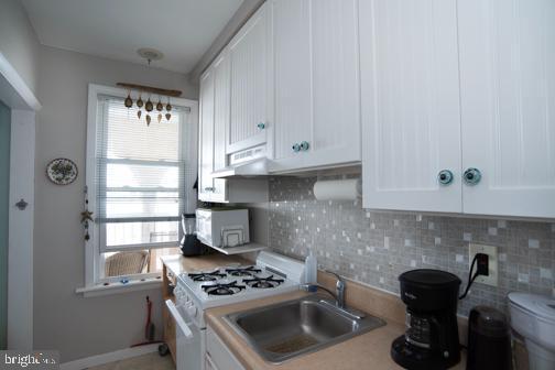 5600 Seaview Ave, Wildwood Crest, NJ 08260 - kitchen with white range with gas cooktop, white cabinetry, range hood, decorative backsplash, and light countertops
