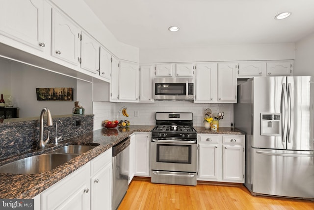 6498 Milva Ln, Springfield, VA 22150 - kitchen with appliances with stainless steel finishes, white cabinetry, dark stone counters, light wood finished floors, and recessed lighting