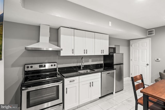 1719 W Norris St, Philadelphia, PA 19121 - kitchen featuring appliances with stainless steel finishes, wall chimney exhaust hood, light marble finish flooring, white cabinets, and dark stone countertops