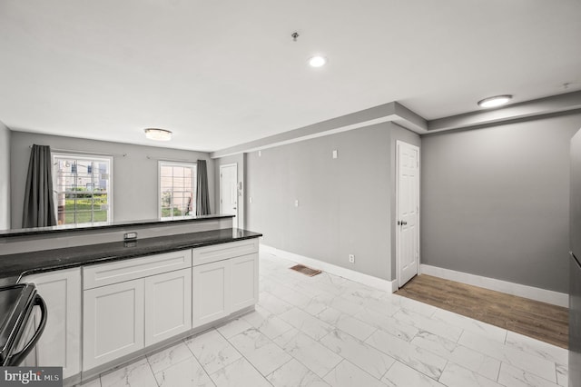 1719 W Norris St, Philadelphia, PA 19121 - kitchen with light marble finish flooring, white cabinets, black stove, recessed lighting, and dark stone countertops