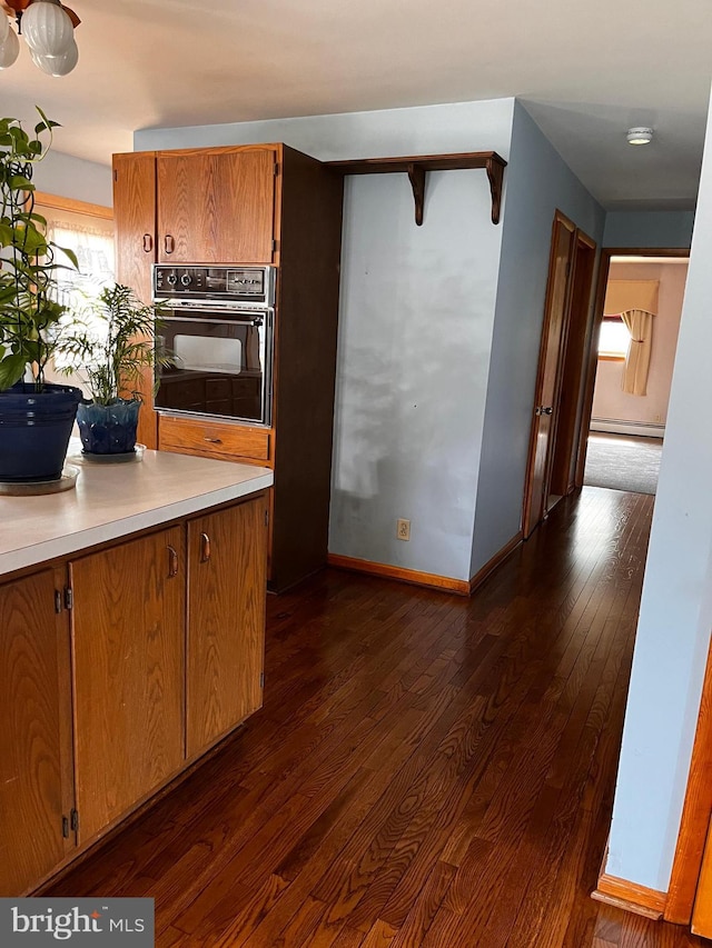 636 Pigeon Creek Rd, Pottstown, PA 19465 - kitchen with black oven, dark wood finished floors, brown cabinets, a baseboard heating unit, and light countertops