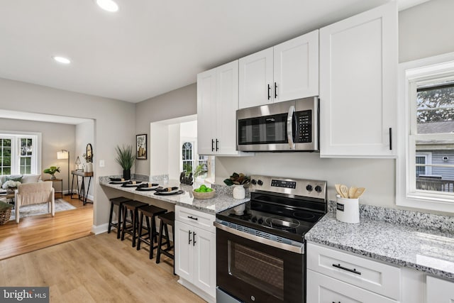 202 Piping Rock Dr, Silver Spring, MD 20905 - kitchen with stainless steel appliances, white cabinets, light wood finished floors, recessed lighting, and light stone countertops