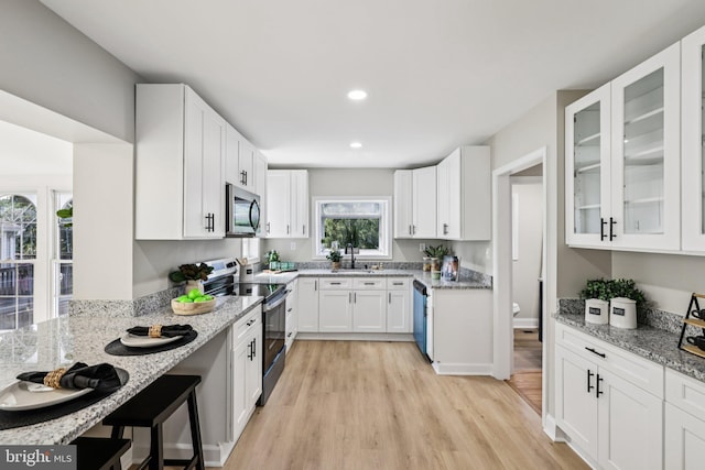 202 Piping Rock Dr, Silver Spring, MD 20905 - kitchen with stainless steel appliances, light wood-style floors, light stone counters, white cabinets, and glass insert cabinets
