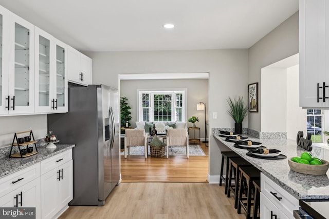 202 Piping Rock Dr, Silver Spring, MD 20905 - kitchen with stainless steel refrigerator with ice dispenser, light wood-style floors, light stone countertops, white cabinetry, and glass insert cabinets
