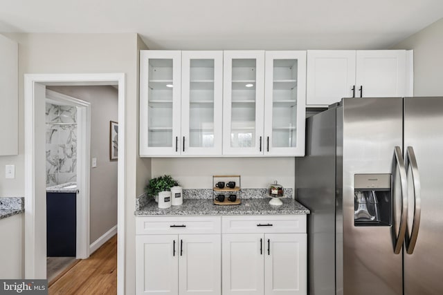 202 Piping Rock Dr, Silver Spring, MD 20905 - kitchen featuring stainless steel refrigerator with ice dispenser, white cabinets, light stone counters, light wood-style flooring, and glass insert cabinets