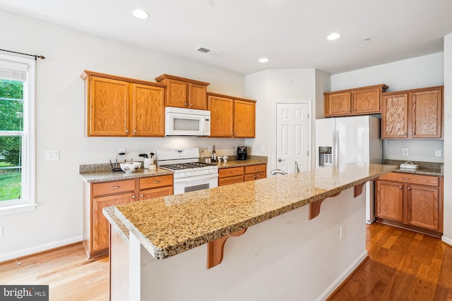 130 Ambrose Ln, Fredericksburg, VA 22406 - kitchen featuring white appliances, a breakfast bar area, wood finished floors, brown cabinets, and recessed lighting