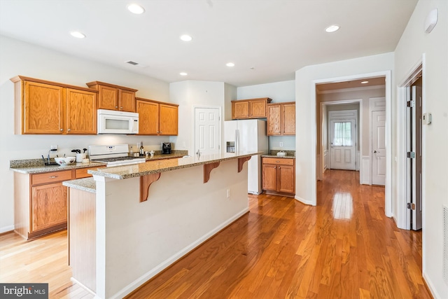 130 Ambrose Ln, Fredericksburg, VA 22406 - kitchen featuring white appliances, a breakfast bar area, brown cabinetry, light wood-style floors, and recessed lighting