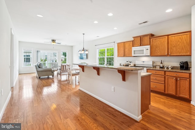 130 Ambrose Ln, Fredericksburg, VA 22406 - kitchen featuring white appliances, brown cabinets, a breakfast bar area, light wood-style floors, and decorative light fixtures