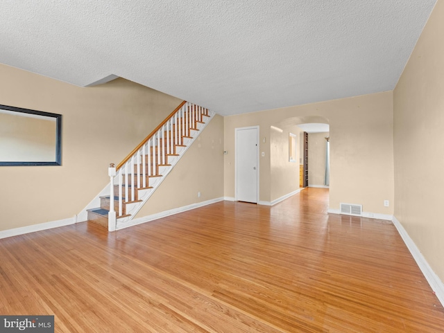 239 Lima St, Philadelphia, PA 19120 - unfurnished living room with arched walkways, stairway, light wood finished floors, and a textured ceiling