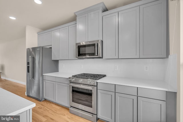9660 Fields Rd Unit 9660, Gaithersburg, MD 20878 - kitchen featuring appliances with stainless steel finishes, gray cabinetry, light wood-style flooring, decorative backsplash, and light countertops