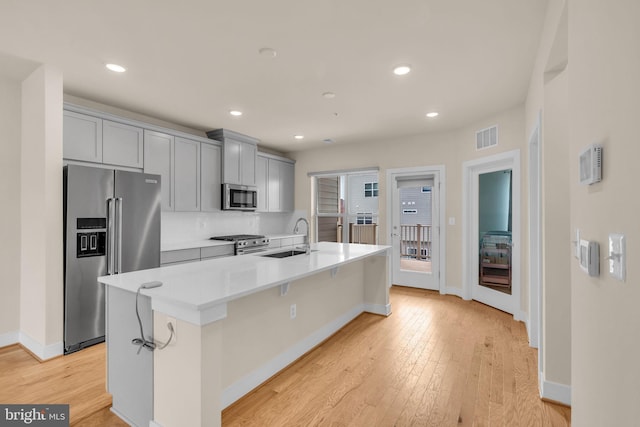 9660 Fields Rd Unit 9660, Gaithersburg, MD 20878 - kitchen featuring high end appliances, gray cabinets, a center island with sink, light wood-style flooring, and light countertops