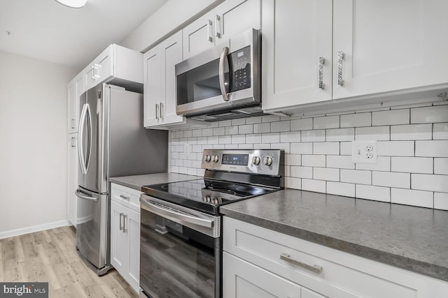 3121 Katewood Ct, Baltimore, MD 21209 - kitchen with appliances with stainless steel finishes, dark countertops, backsplash, light wood-type flooring, and white cabinetry