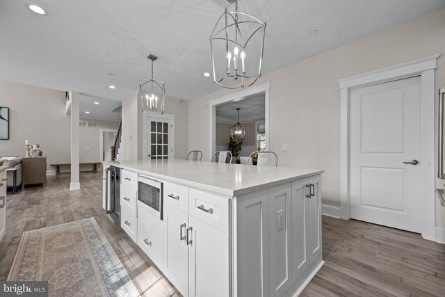 4245 Mechanicsville Rd, Doylestown, PA 18902 - kitchen with a chandelier, stainless steel microwave, open floor plan, a center island, and light wood-type flooring