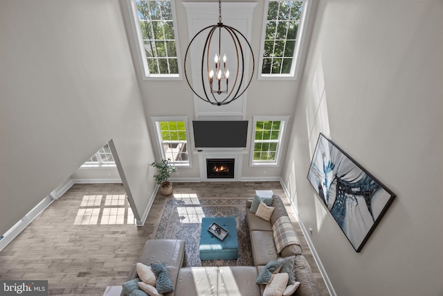 4245 Mechanicsville Rd, Doylestown, PA 18902 - living room with a chandelier, a towering ceiling, wood finished floors, and a lit fireplace