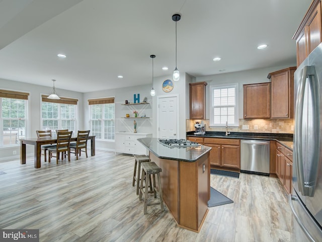 7436 Pensacola Pl, Gainesville, VA 20155 - kitchen featuring stainless steel appliances, light wood finished floors, dark countertops, brown cabinets, and healthy amount of natural light