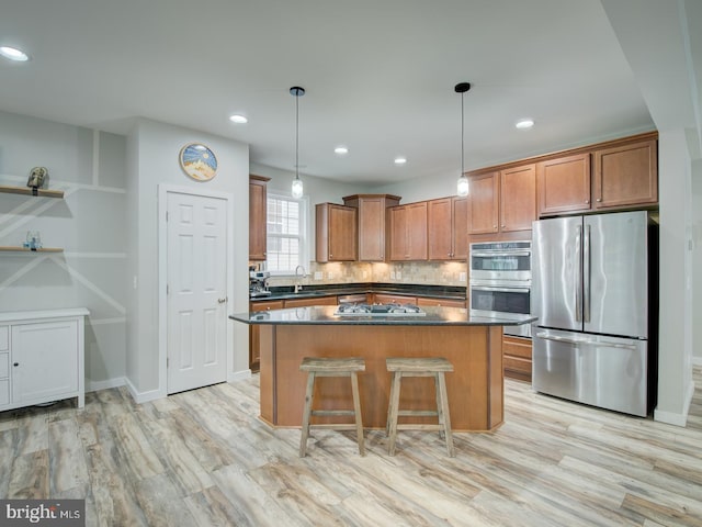 7436 Pensacola Pl, Gainesville, VA 20155 - kitchen with stainless steel appliances, dark countertops, a center island, light wood-style flooring, and hanging light fixtures