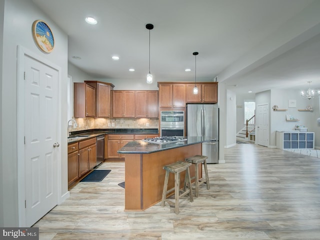 7436 Pensacola Pl, Gainesville, VA 20155 - kitchen with appliances with stainless steel finishes, dark countertops, a center island, light wood-style flooring, and brown cabinetry