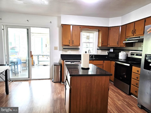 6529 Huntshire Dr, Elkridge, MD 21075 - kitchen featuring stainless steel appliances, under cabinet range hood, wood finished floors, a kitchen island, and dark countertops