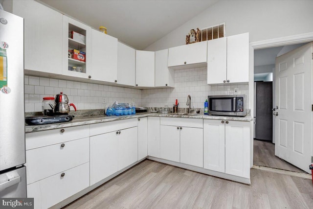 301 Broad St, Beverly, NJ 08010 - kitchen with stainless steel microwave, light wood-type flooring, backsplash, lofted ceiling, and white cabinets