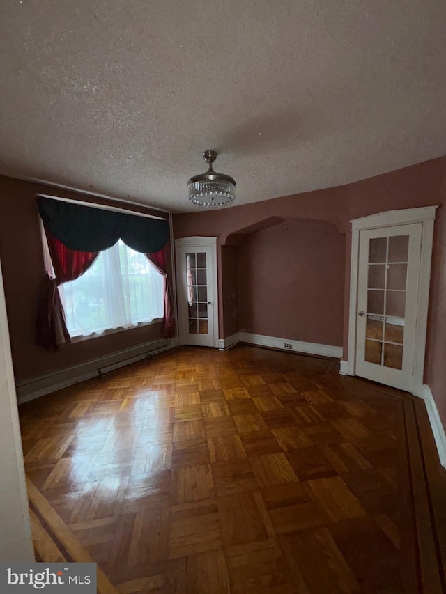 5122 Stenton Ave, Philadelphia, PA 19144 - empty room with a textured ceiling, arched walkways, and baseboard heating