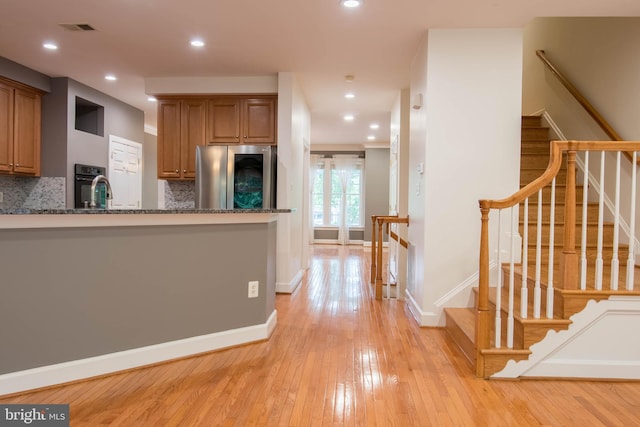 114 Herndon Mill Cir, Herndon, VA 20170 - kitchen featuring stainless steel refrigerator, light wood-style flooring, black oven, tasteful backsplash, and brown cabinets
