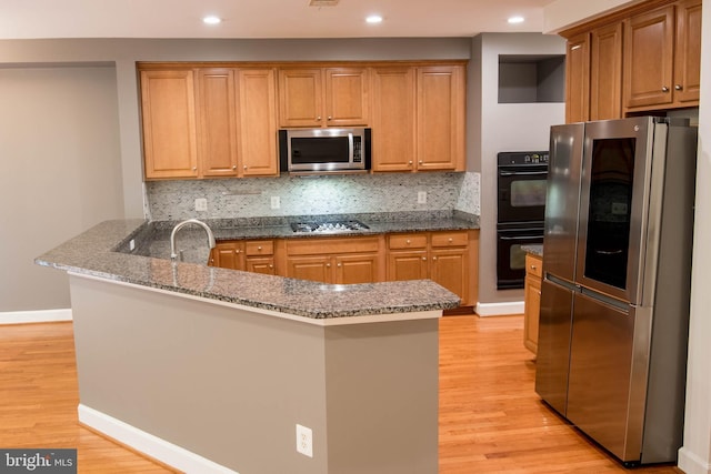 114 Herndon Mill Cir, Herndon, VA 20170 - kitchen featuring stainless steel appliances, a peninsula, light wood-style flooring, backsplash, and dark stone counters