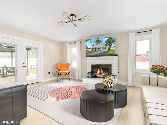 13222 Parson Ln, Fairfax, VA 22033 - living room with light wood finished floors, a brick fireplace, a chandelier, and french doors